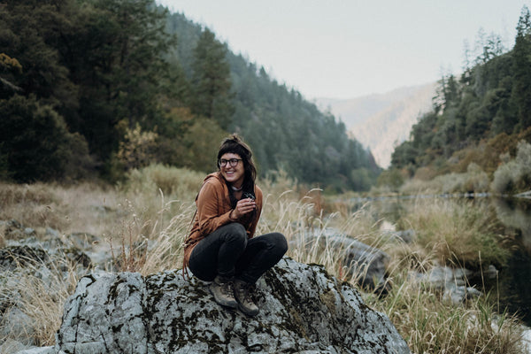 Woman on a boulder in the outdoors smoking hemp CBD