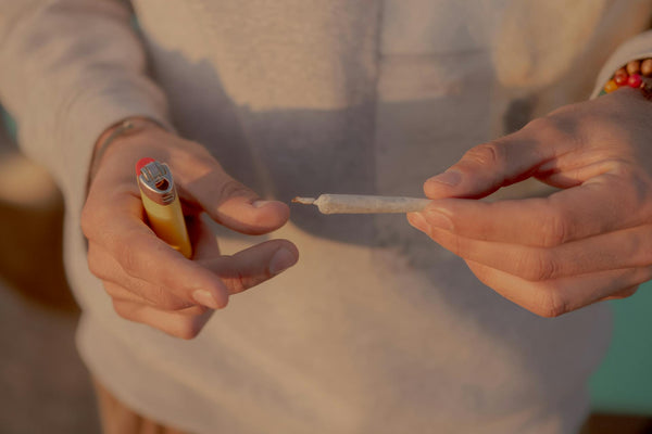 person holding a rolled hemp cone and lighter